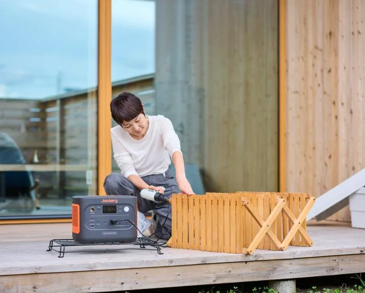 Jackery ポータブル電源 1500 Newをデッキで使い、木製の折りたたみ家具を扱う人