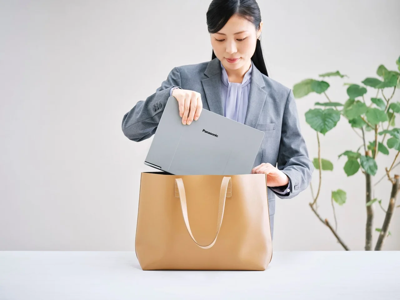 軽量ボディの13.3型レッツノートをトートバッグに入れるスーツ姿の女性
