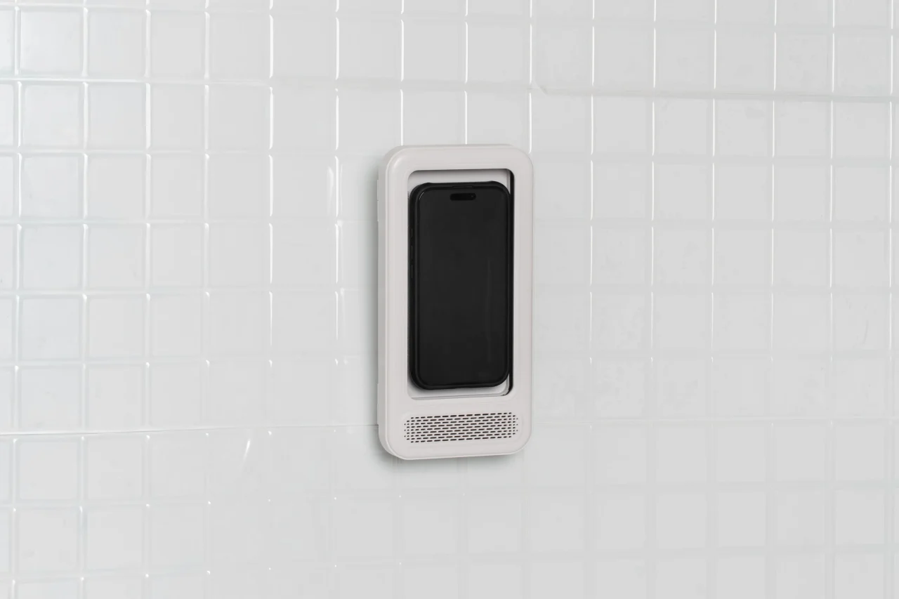 白いタイル壁に取り付けた縦型のスマホ防水ケース。下部にスピーカーポート