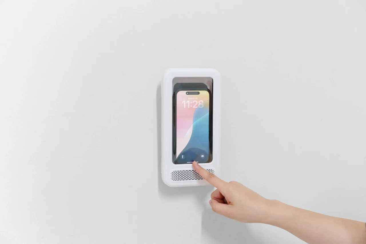 スマホ防水君 縦型Plusに収納したスマホを壁際で指で操作する様子