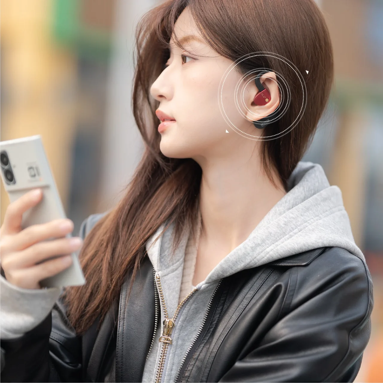 デュアルマイク・ビームフォーミングENC：耳に赤いイヤーフックを着けスマホを持つ女性