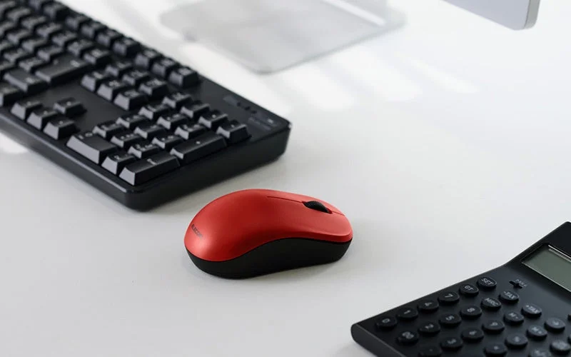 Bluetooth接続モデルのレッドの3ボタンマウス。キーボードと電卓の近くに置かれている