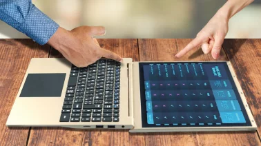 ディスプレイが180度開いたフラット状態のノートPCと、画面を指差す二人の手