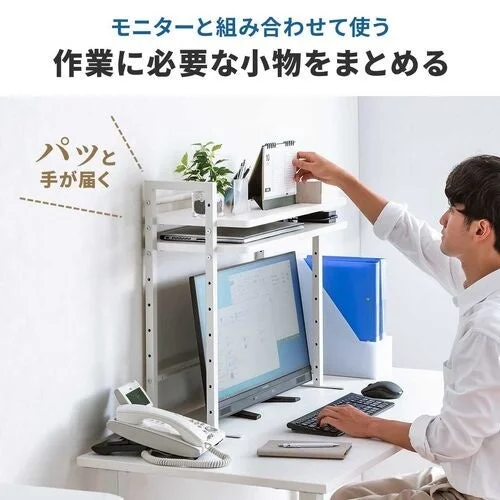 モニターを高くして使う机上ラックと、棚の小物に手を伸ばす男性