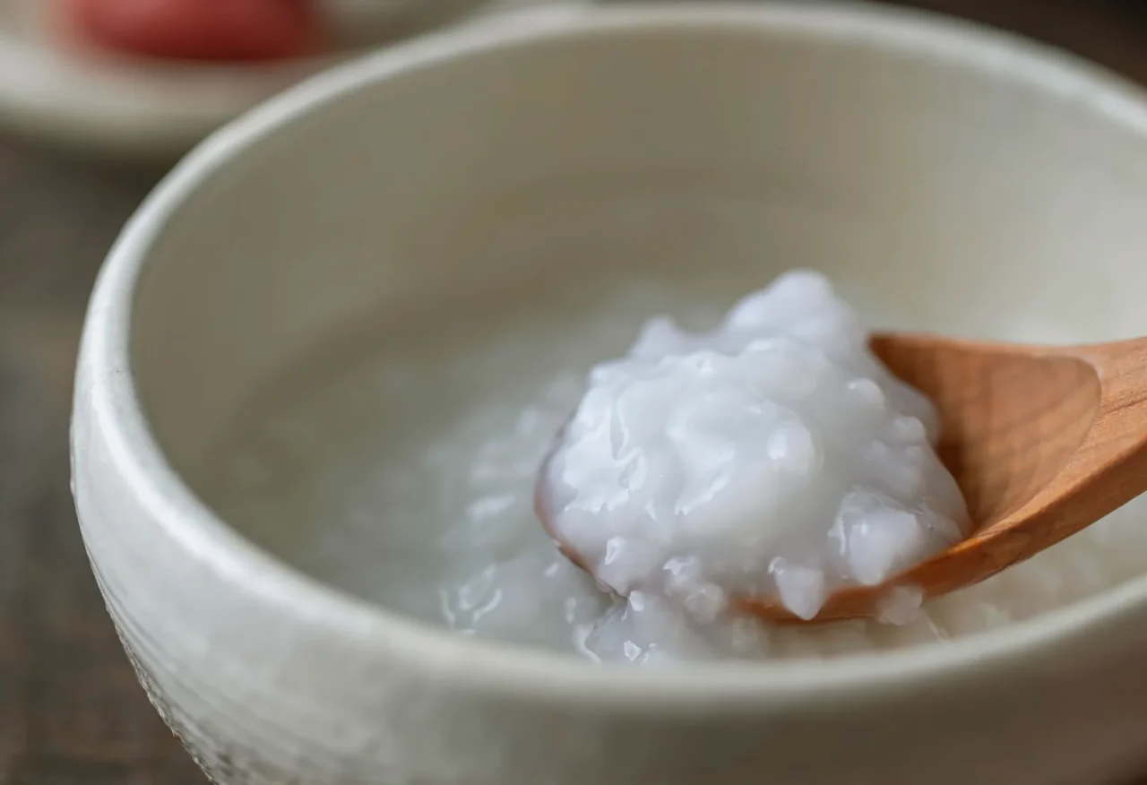 白い器に入ったおかゆを木のスプーンですくった様子