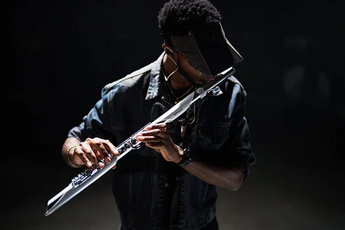「Aerophone Brisa」を構える演奏者。暗背景でデニム姿