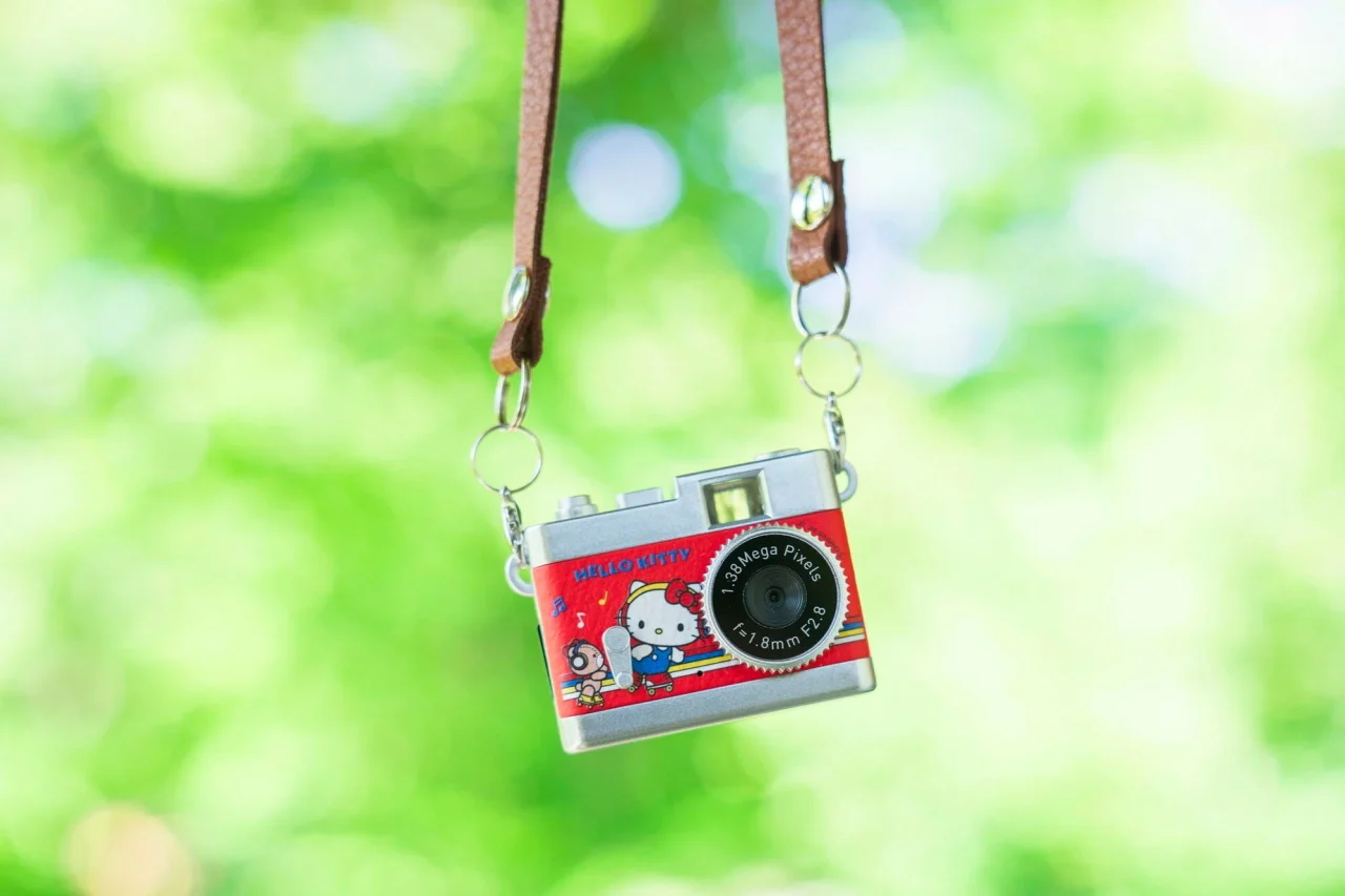 緑の木々を背景に吊るされたサンリオキャラクター トイカメラ STREET