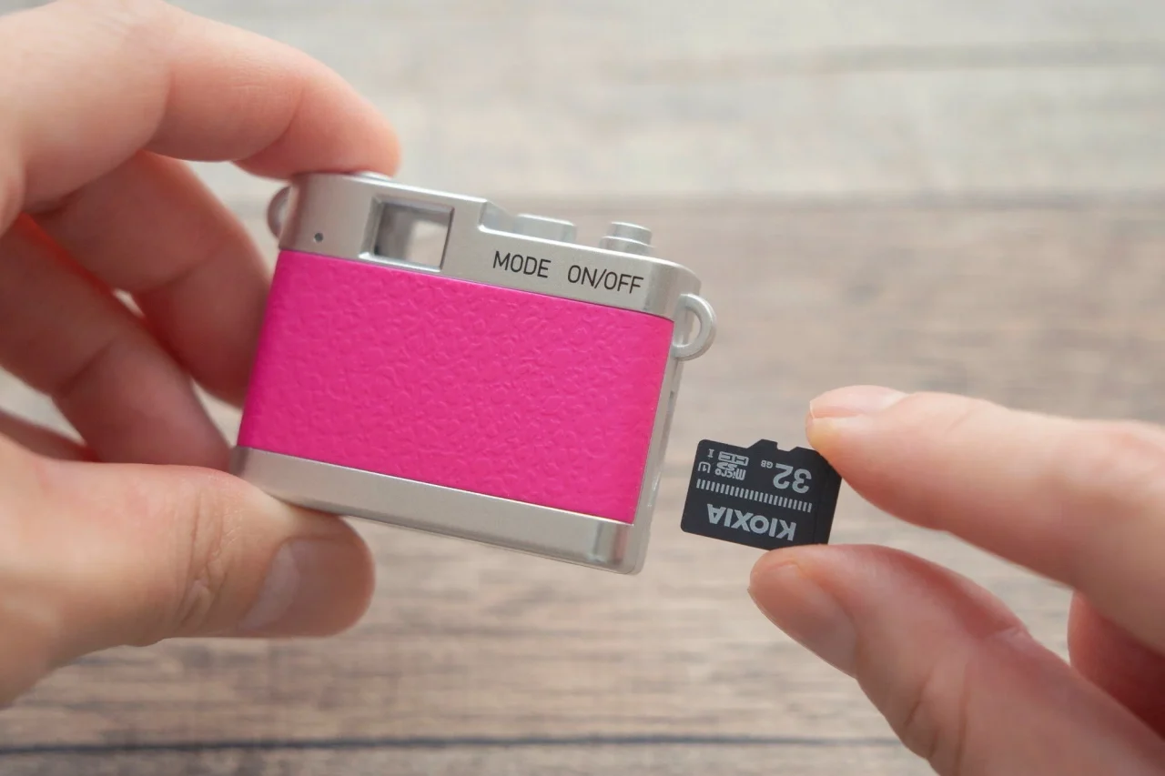 ピンクの超小型トイカメラとmicroSDカードを持つ手