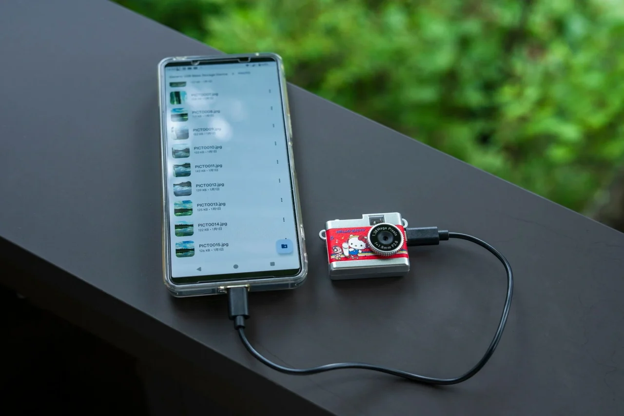 スマートフォンとUSBケーブルでつないだ赤いトイカメラ