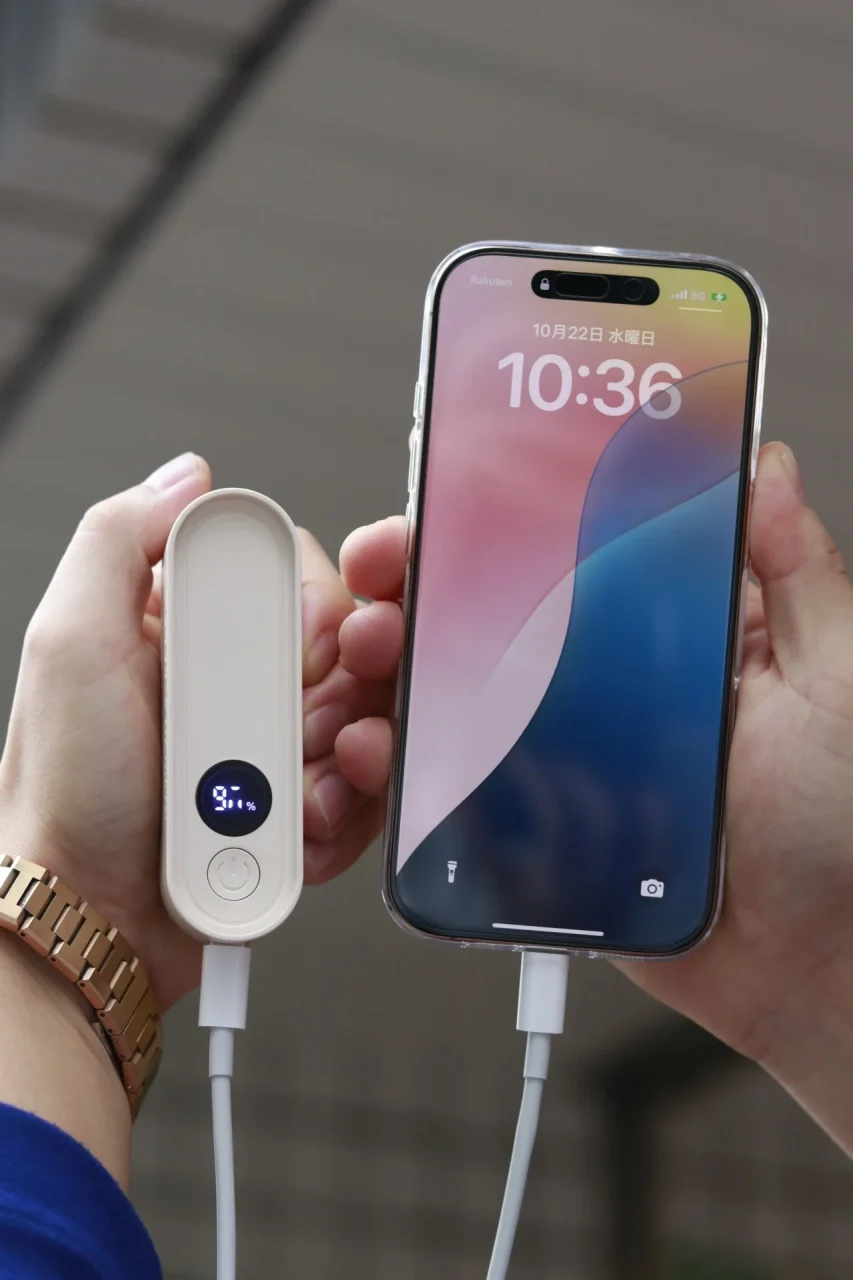 分離した電子カイロ片方でスマホを充電する様子、残量表示付き