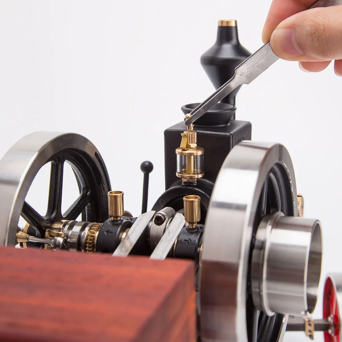 HM-01のフライホイール、透明なオイルカップ、真鍮部品を指先の工具で調整する様子