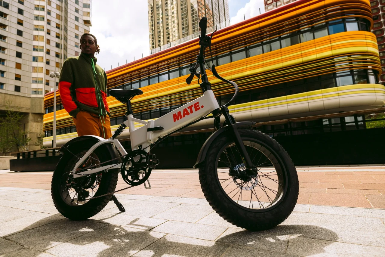 ビル前に停めたMATE X EVO。太いタイヤの白いe-BIKEと隣に立つ男性