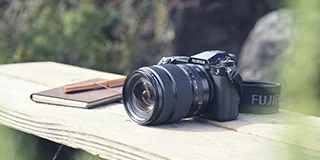 木の台に置かれたFUJIFILMのデジタルカメラと手帳