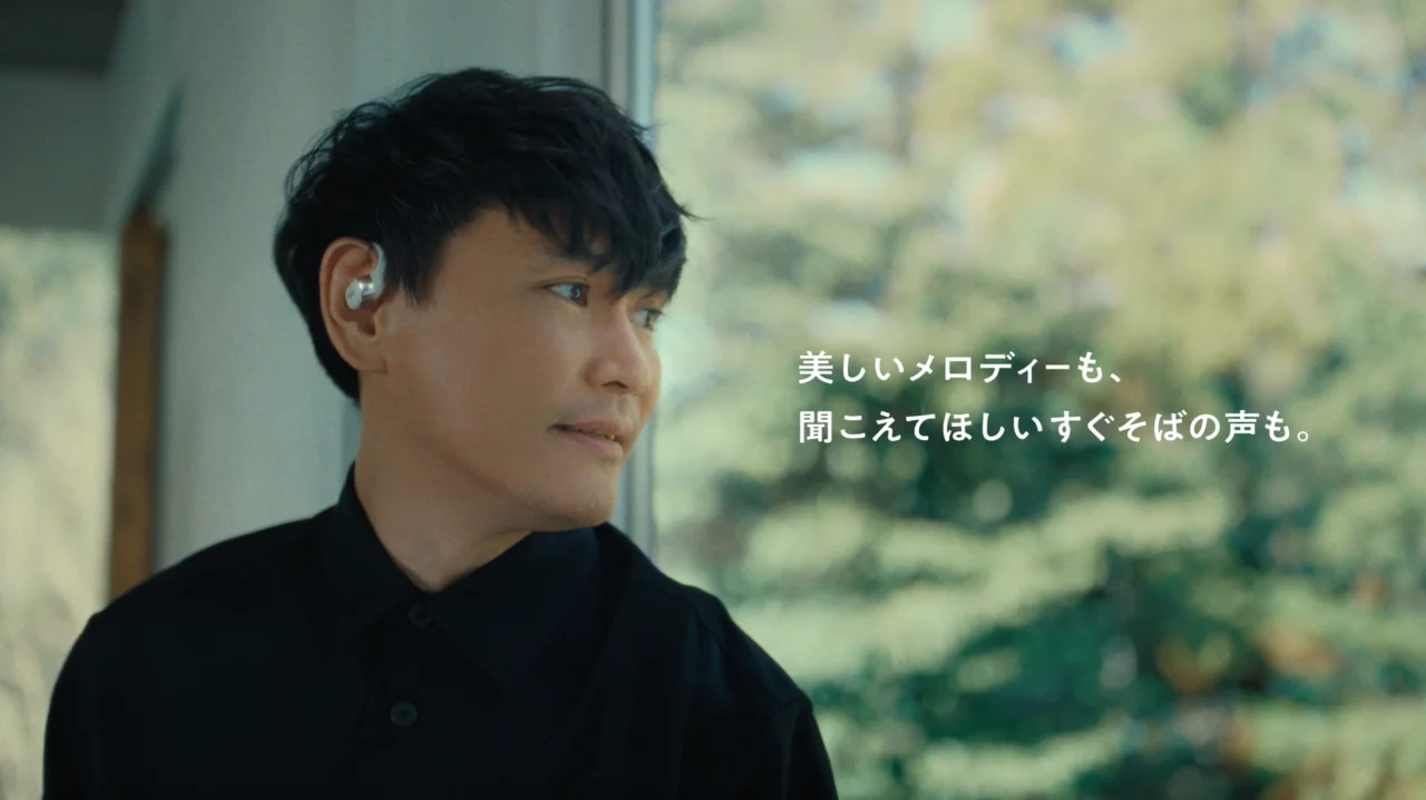 耳掛け型イヤホンを片耳に着けた黒いシャツの男性と、コピーの文字