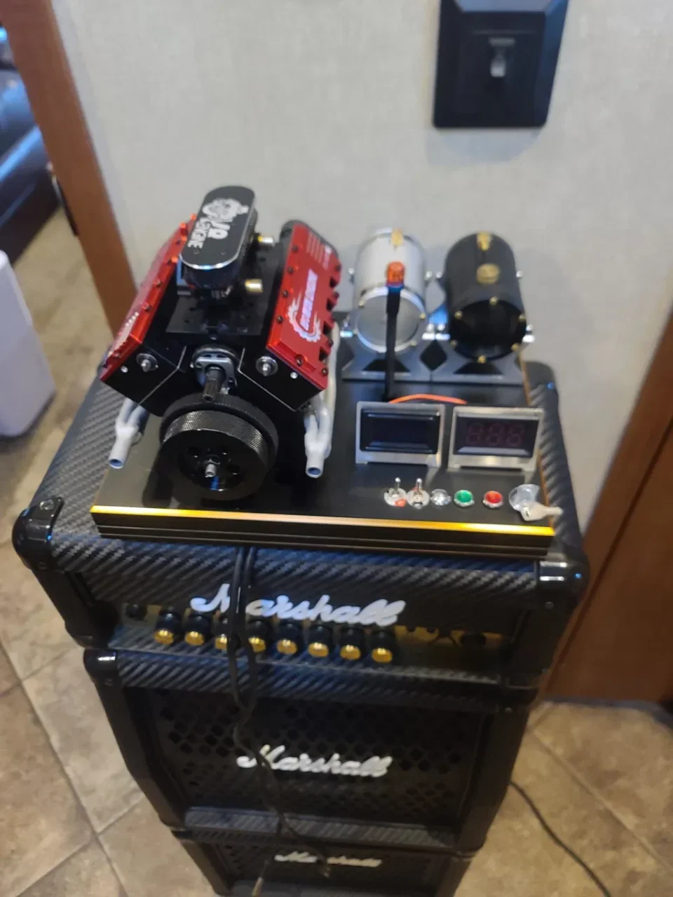 Marshallアンプ上に置かれた赤いV8エンジン模型とメーター付きの台