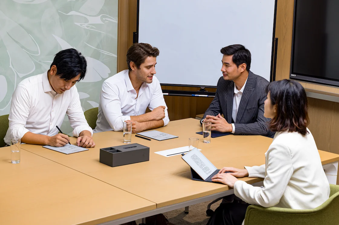 iFLYTEK AINOTE 2を使い会議室で打ち合わせをする4人のビジネスパーソン