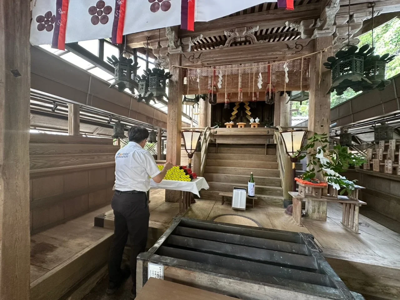 京都に座す火伏の神社の社殿で白い服の男性が供え物を整える様子