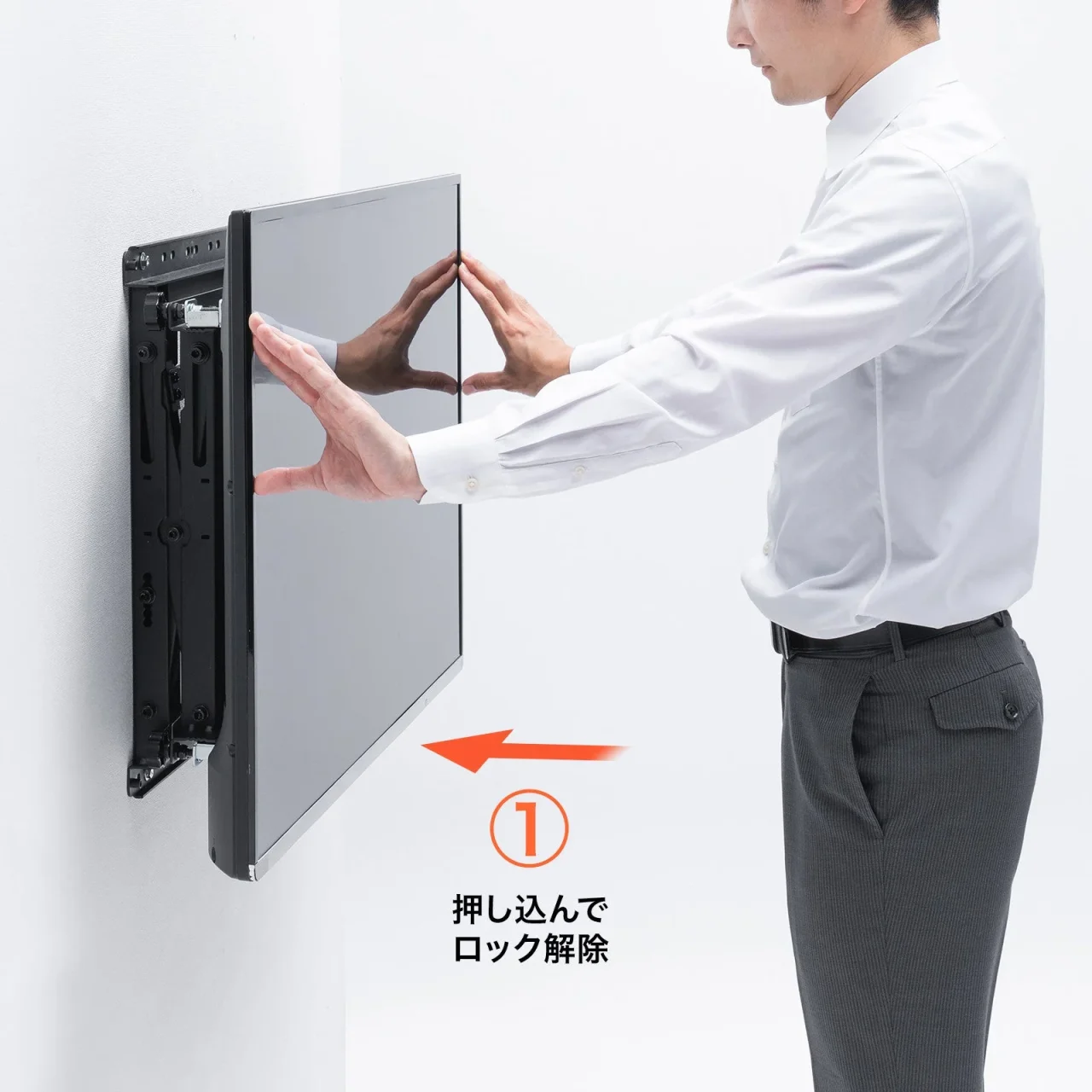 壁掛け金具のディスプレイを手で押し込みロック解除する男性
