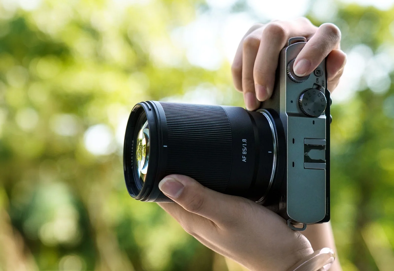 Neo AF 85mm f/1.8を装着したカメラを両手で構える様子