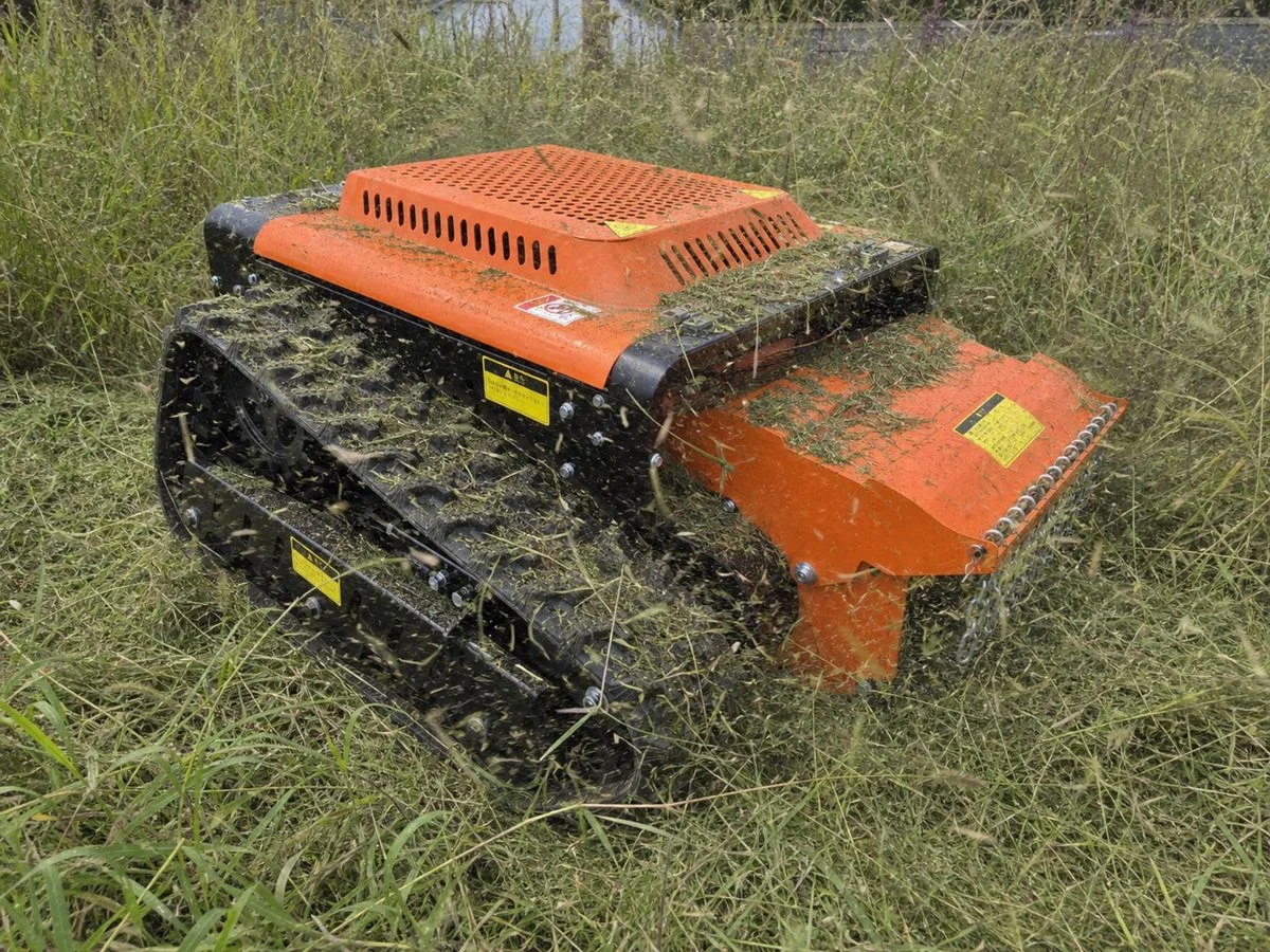 JRSY500作業イメージ1。草地で刈草をまとうオレンジ色のクローラー式草刈機