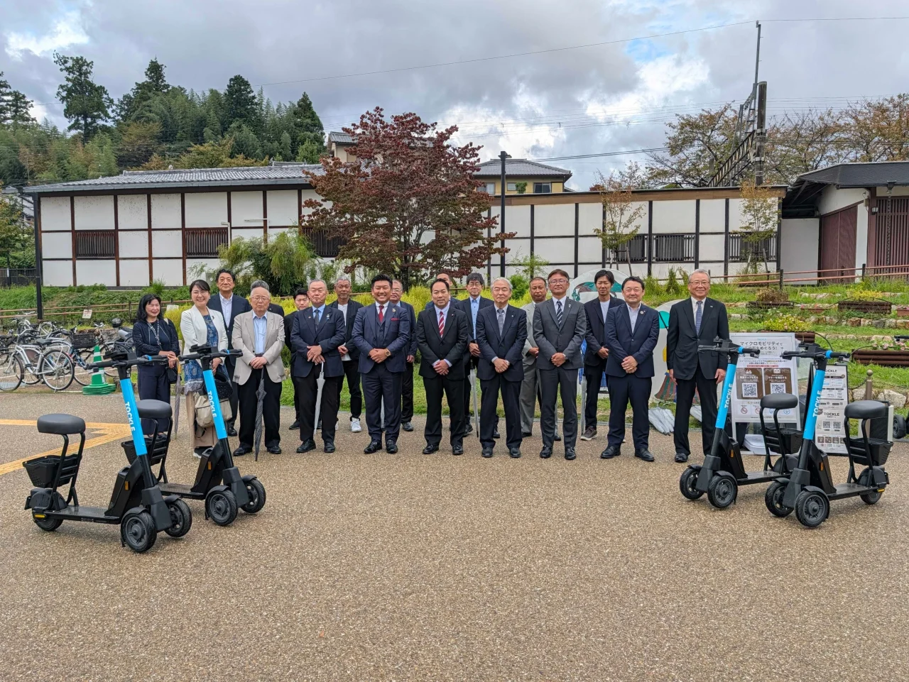 BRJと明日香村の関係者の集合写真と両脇の三輪電動モビリティ