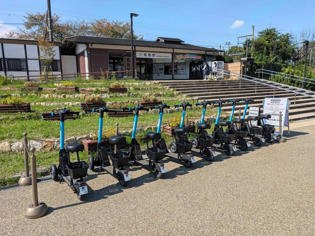 駅前の広場に並んで駐車された水色フレームの三輪電動シートボード