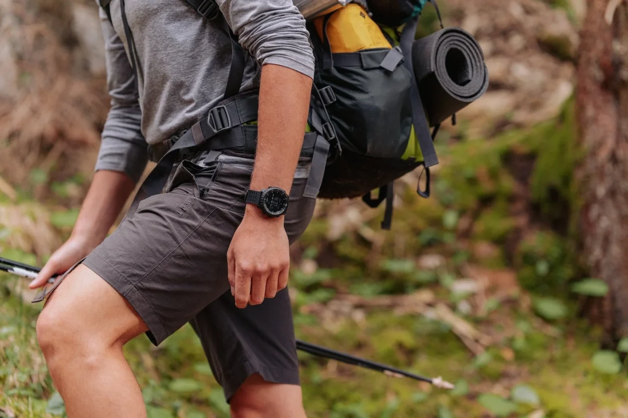 初代Suunto Coreを思わせる黒い腕時計を着け、山中を歩くハイカー