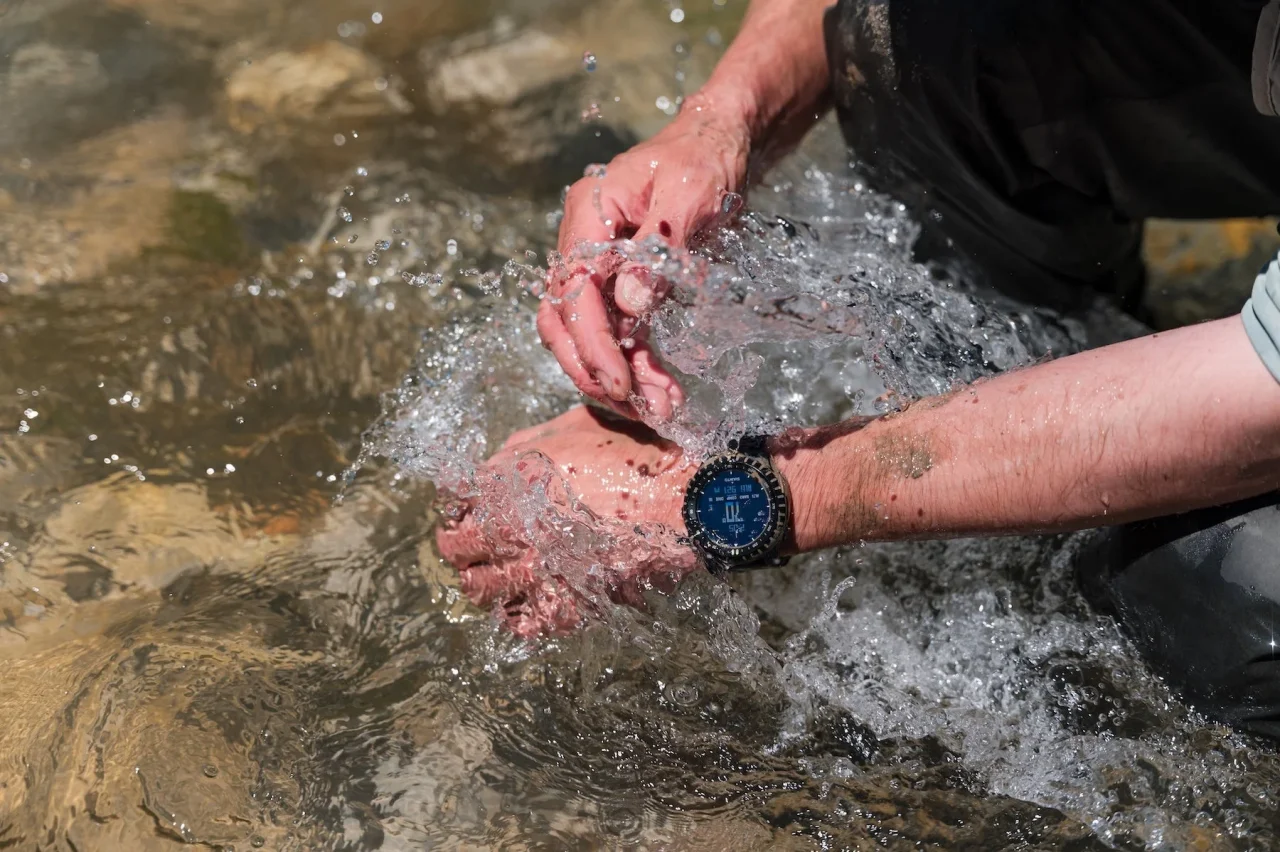 川の水に手を浸し水しぶきが上がる、腕に着けたCore 2ウォッチ