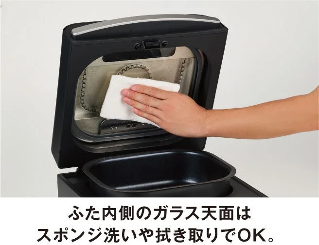 ふた内側のフラットなガラス天面を手で拭き取るお手入れの様子