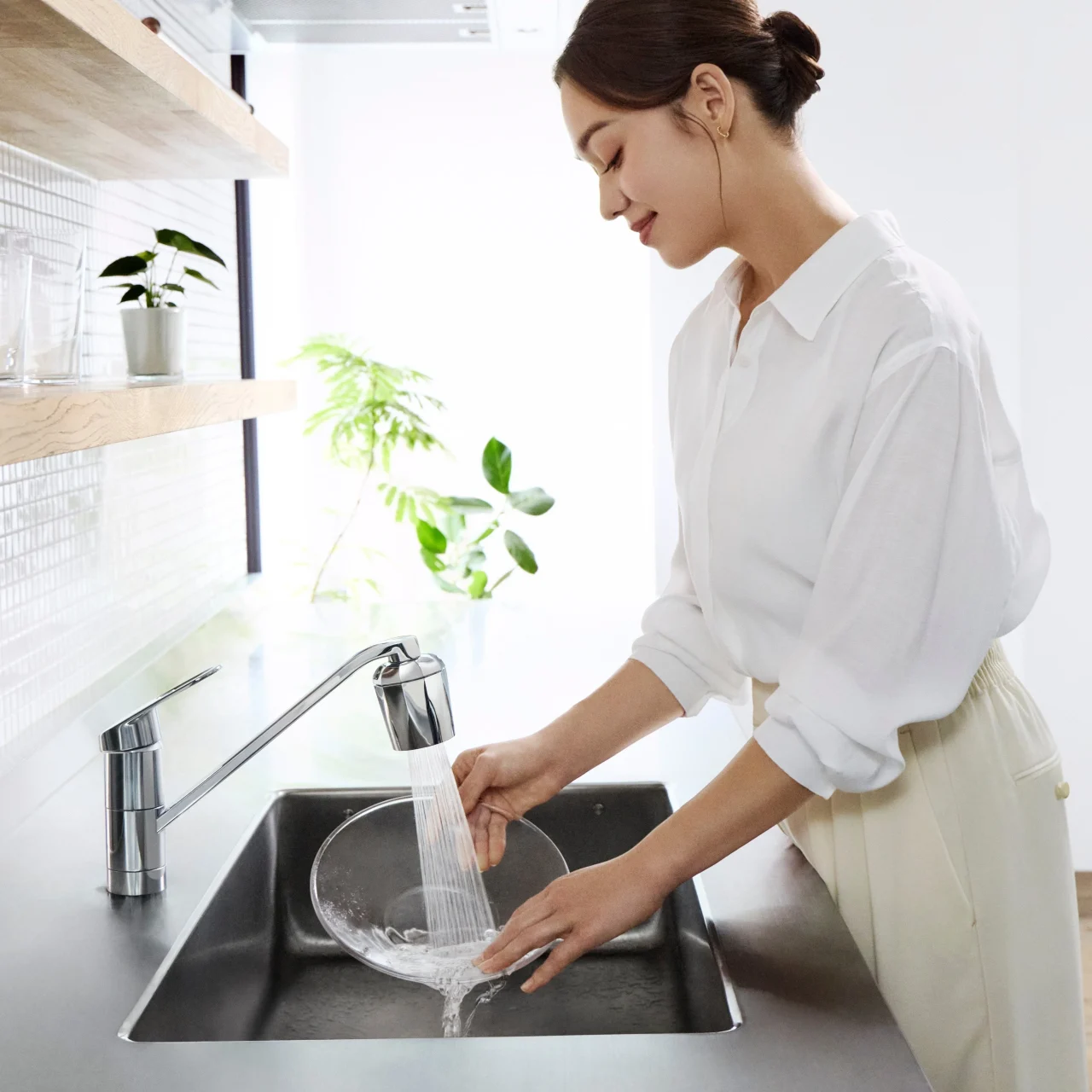 キッチン水栓で食器を洗う女性。ReFa ULTRA FINE BUBBLE KITCHENの使用イメージ