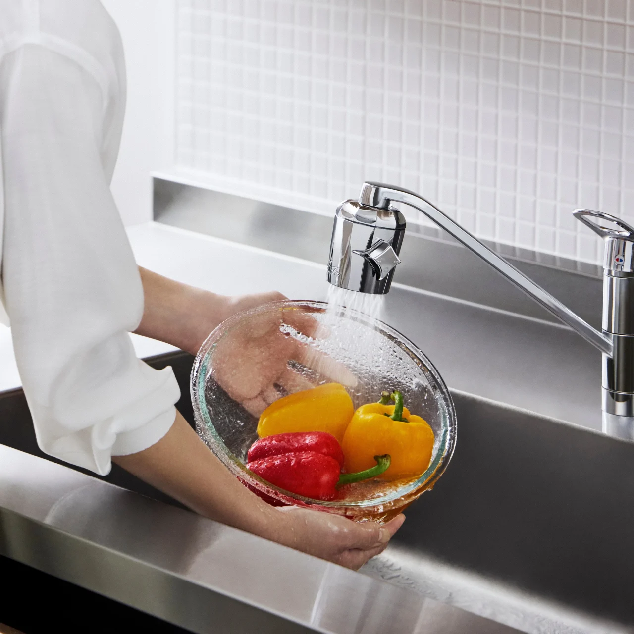 キッチン水栓の水でパプリカをガラスボウルで洗う手元