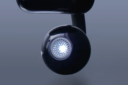 耳元を照らす健光浴®の光を放つ黒い丸型イヤホン部のアップ