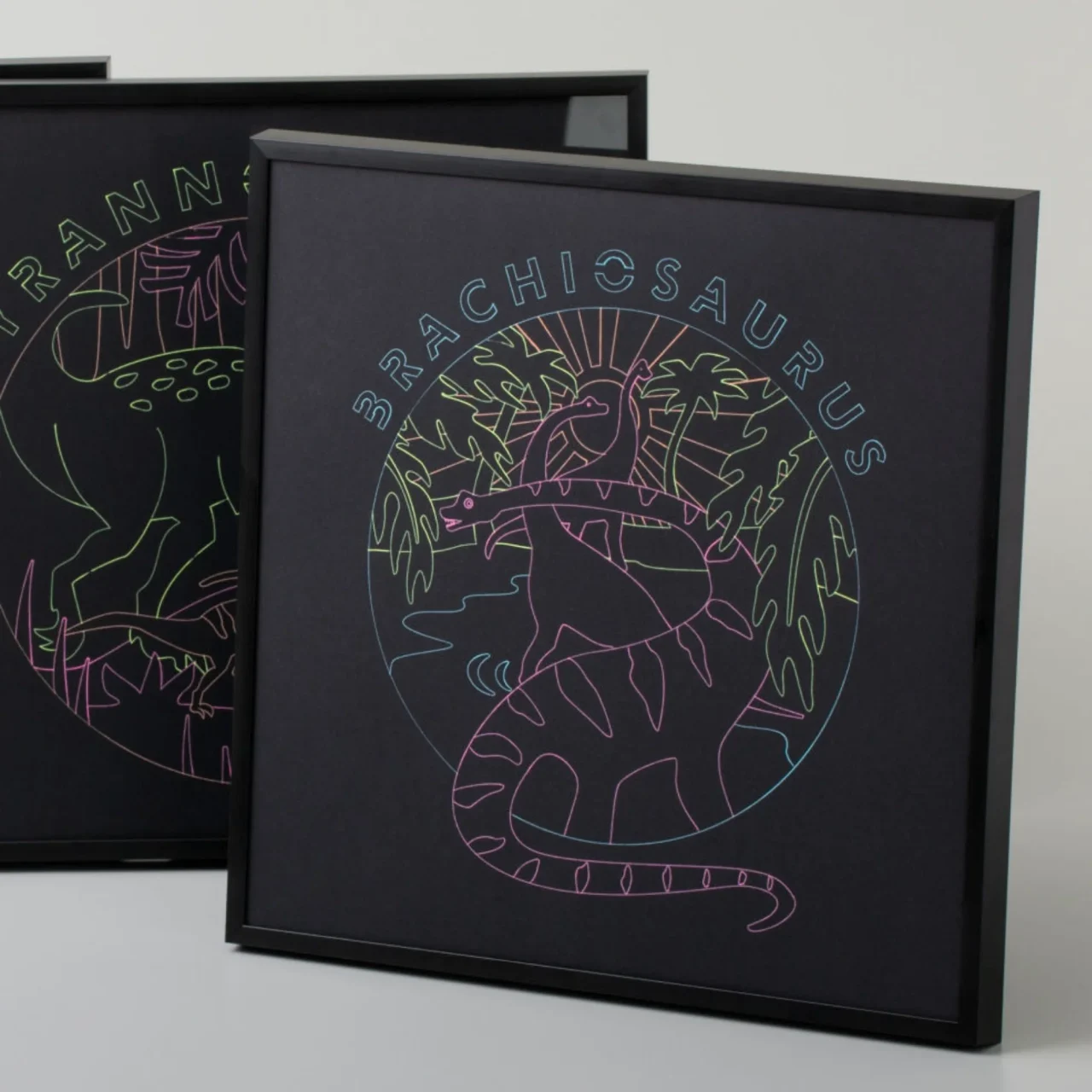 黒い用紙にカラフルなラインで描かれた恐竜イラストの額入り作品