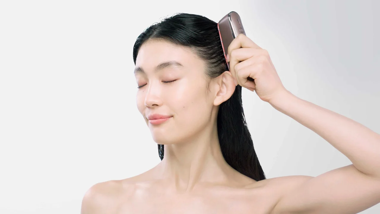 スカルプ電気ブラシを頭皮に当てる、目を閉じた女性