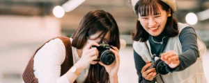 カメラを構えて撮影した写真を見て笑顔を見せる二人の女性