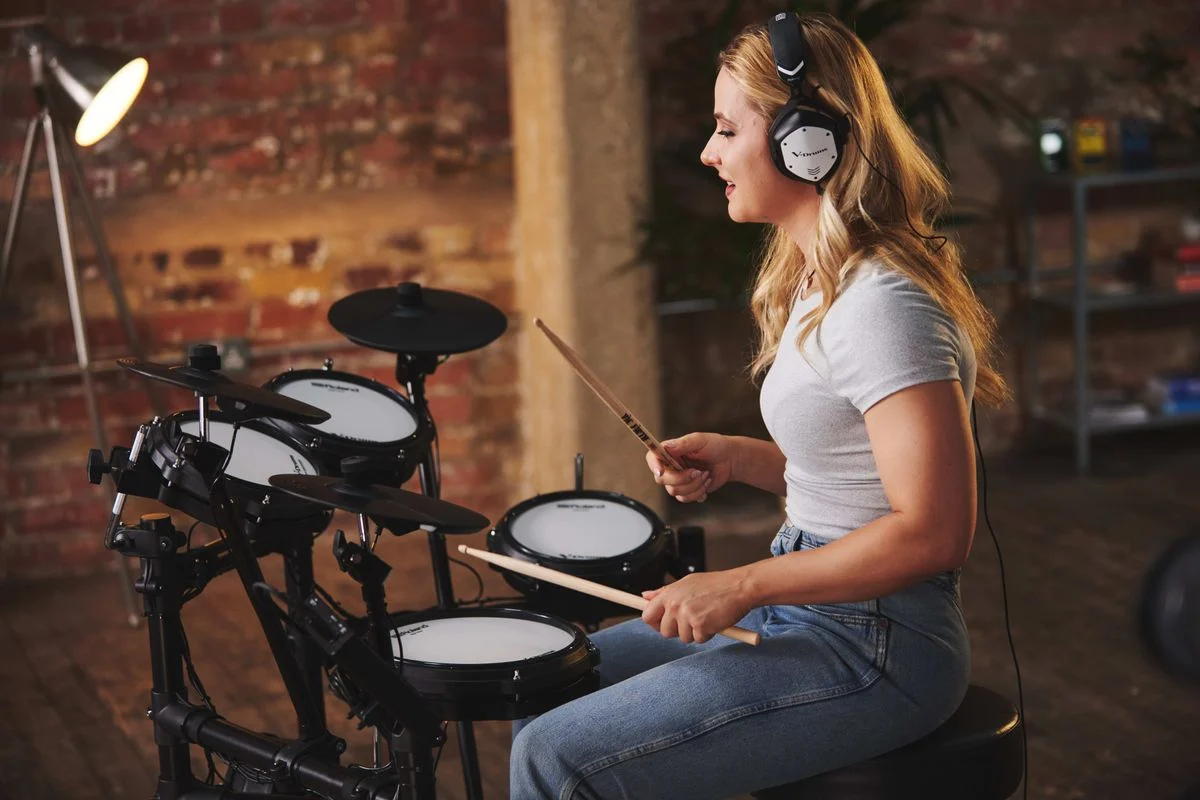 『TD-07DMK2』 演奏イメージ。ヘッドホンの女性が電子ドラムを叩く