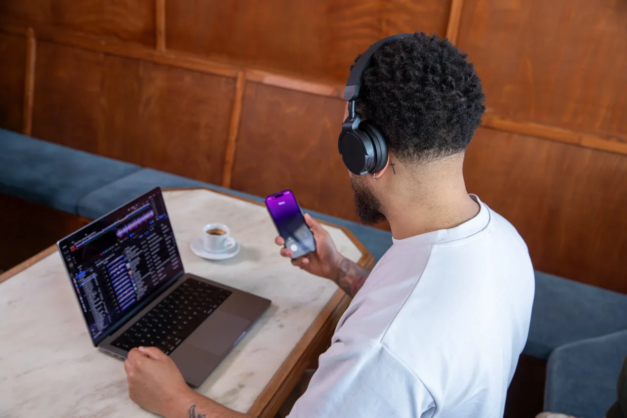 HDJ-F9を装着し、スマートフォンを手にノートPCの前に座る男性