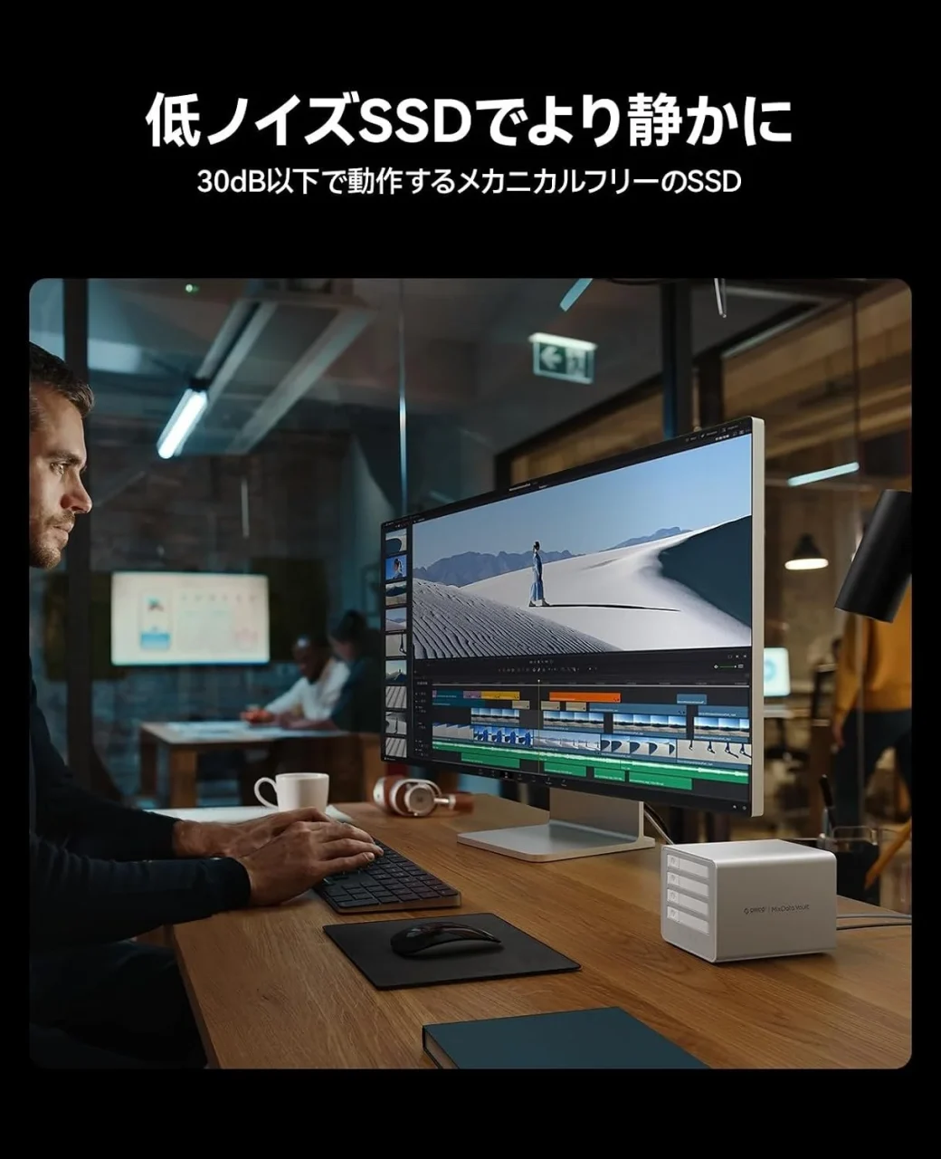 低ノイズSSDで静かに。デスクのモニター横に置かれた白いSSDケースと作業する人物