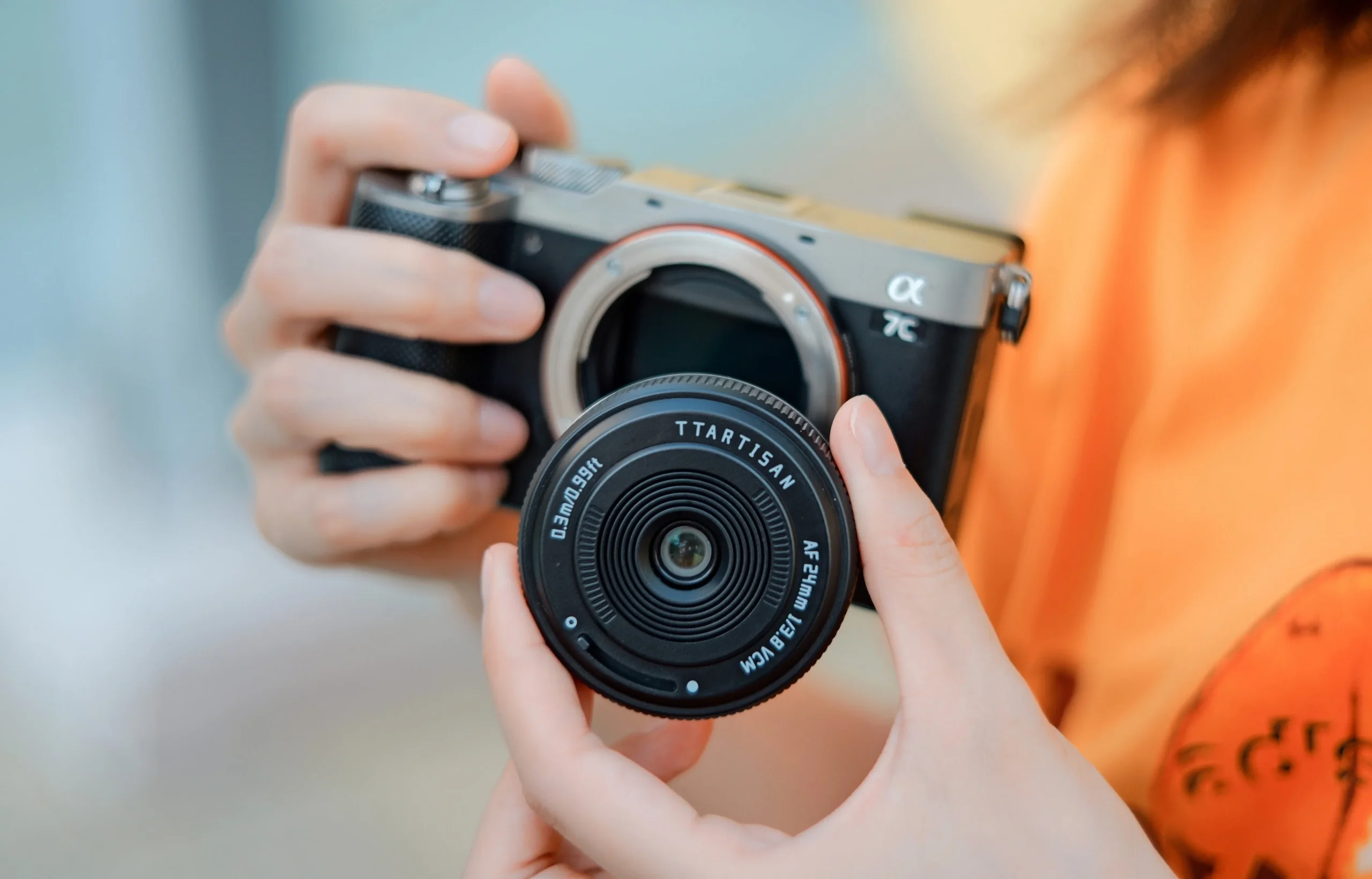 TTArtisan mini AF 24mm f/3.8を手に持ち、カメラに装着しようとする様子