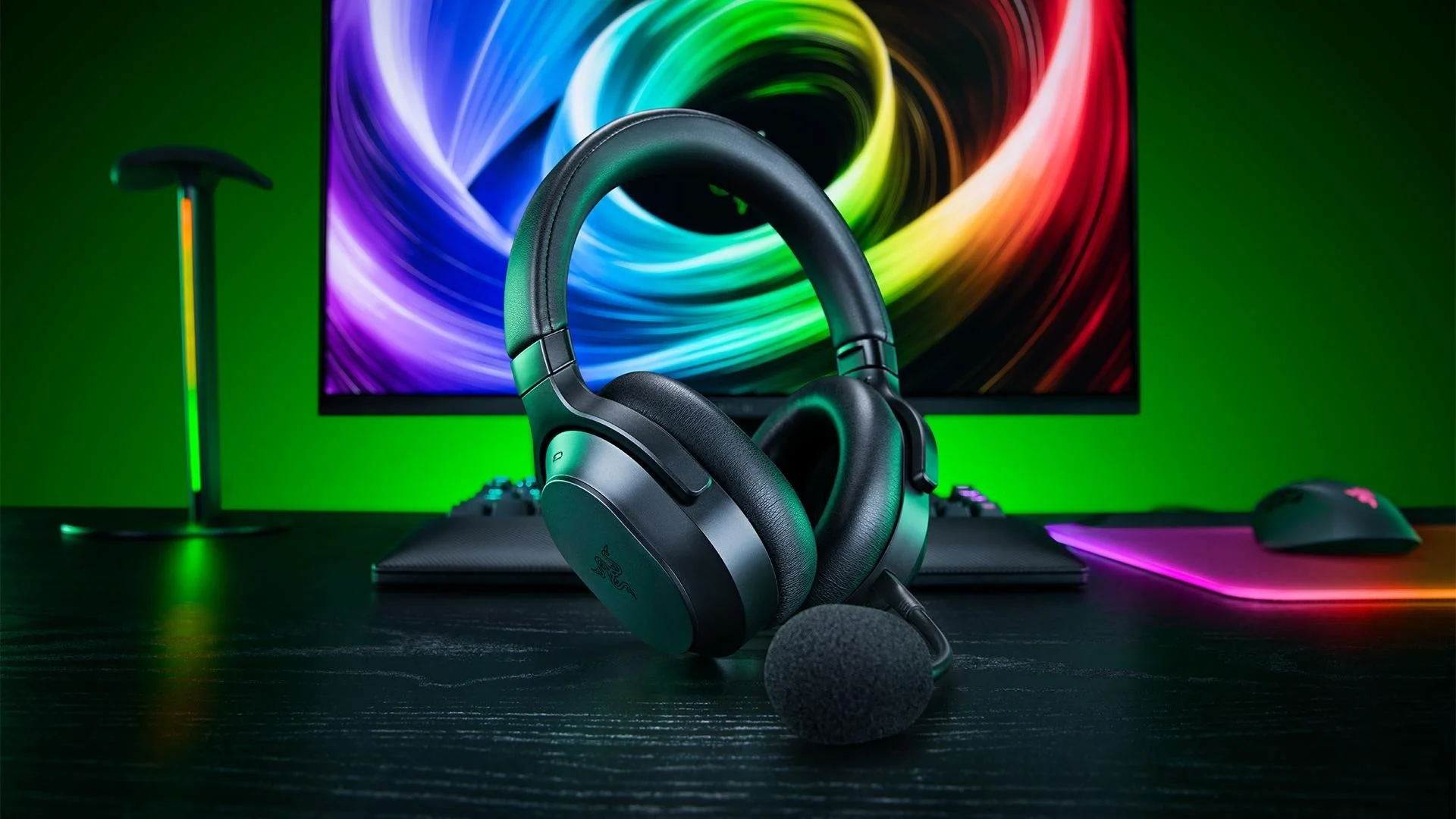 Razer Barracuda V2 Proのブラックのヘッドセットとマイク、背景にゲーミングデスク