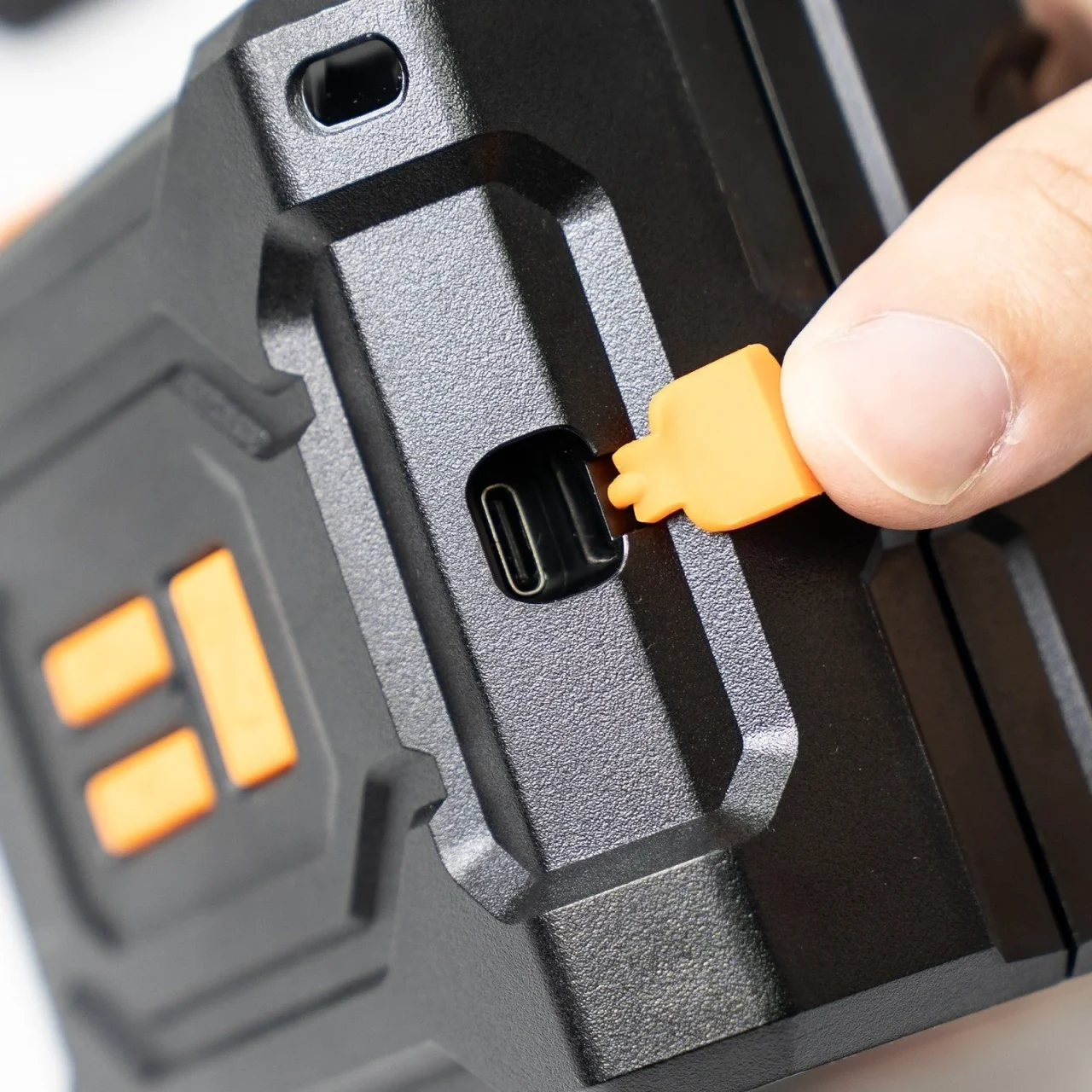 USB Type-C充電ポートのゴム製オレンジのカバーを指で外す黒い本体
