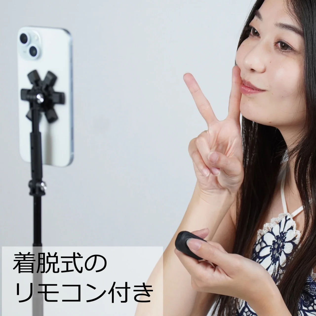スマホを装着したスタンドとリモコンを持つ女性。着脱式のリモコン付き