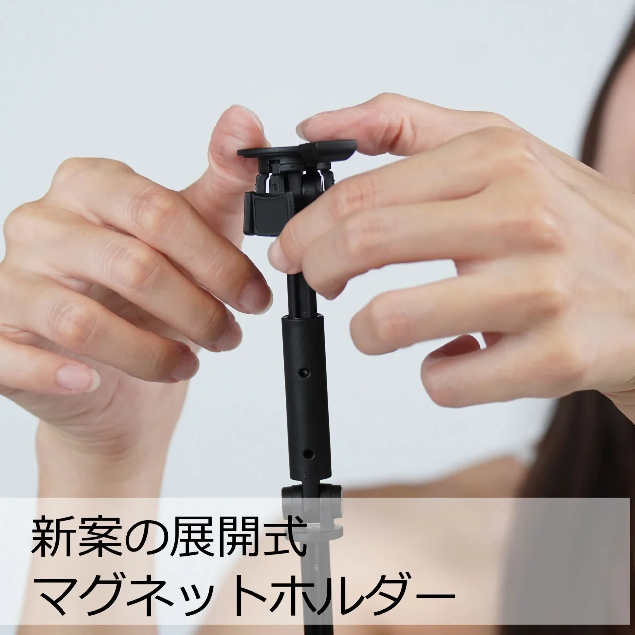 展開式マグネットホルダーを両手で操作する、黒いスリック マグクイックポップスタンド