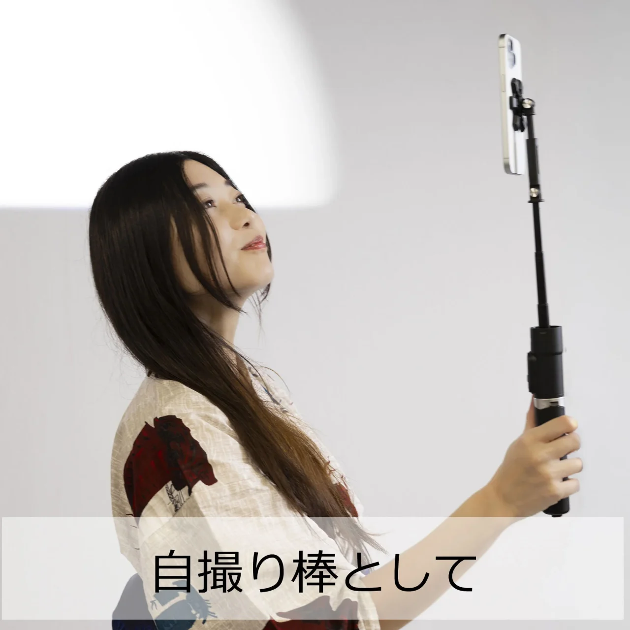 自撮り棒として使う例。長髪の女性がスマートフォンを掲げている