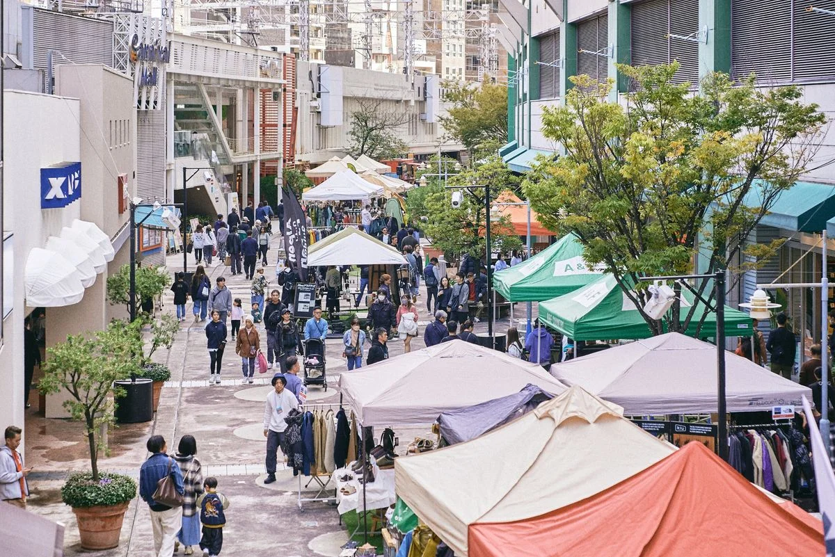 会場風景 1。テントが並ぶ屋外通路を多くの来場者が歩く様子