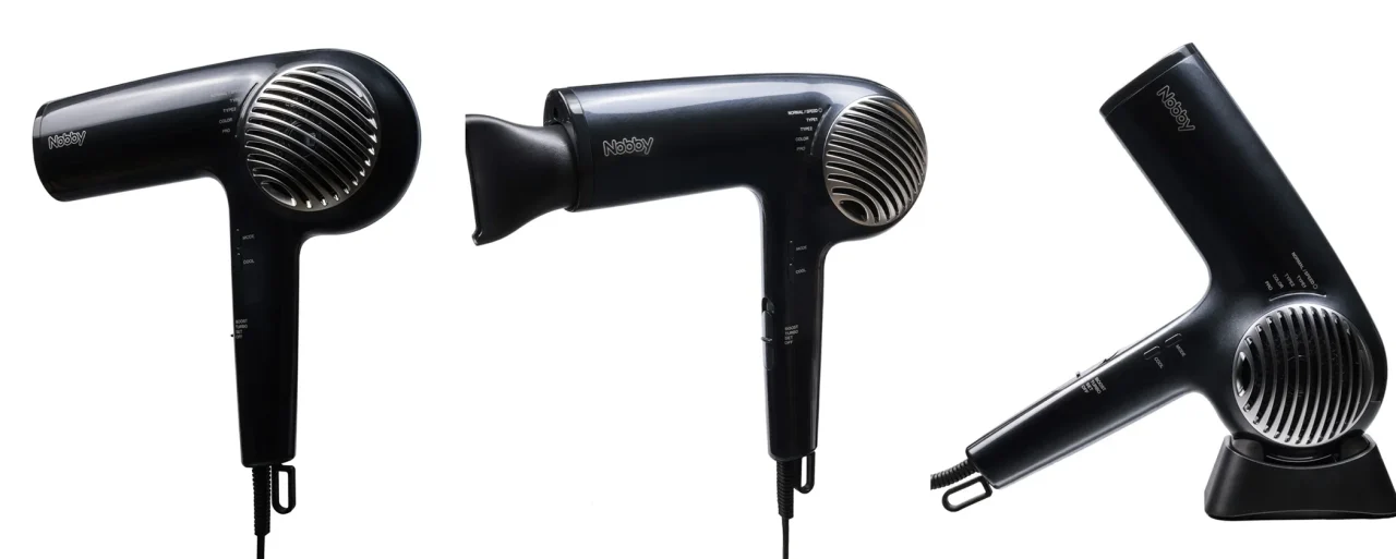 Nobbyロゴ入りの黒いヘアドライヤー3点。正面、ノズル付き、スタンド設置