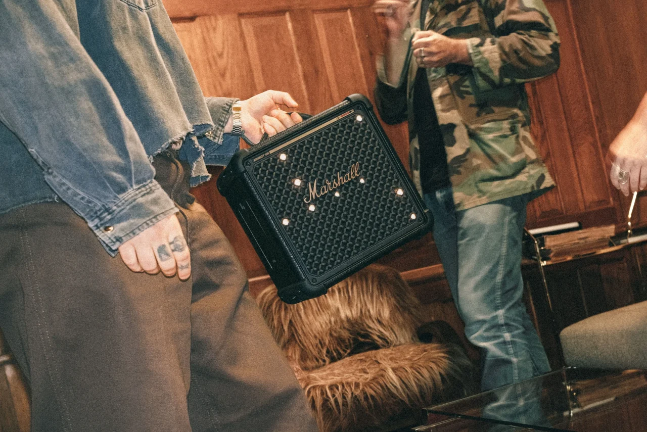 Bromley 150を手に持つ人。黒いグリルにライトが点灯するMarshallスピーカー