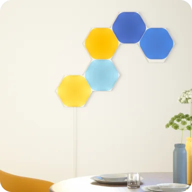 壁に配置したNanoleaf Shapesの六角形パネル。黄・水色・青に点灯