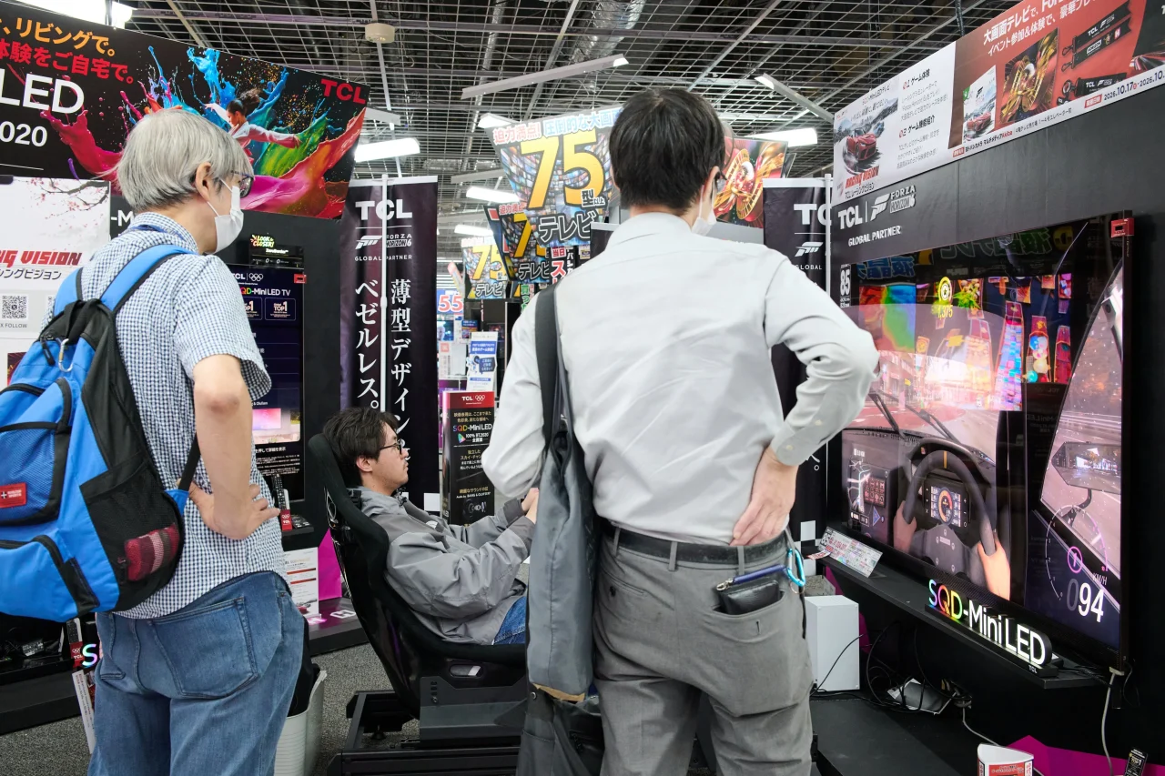 TCLの大画面テレビでレーシングシミュレーターを体験する来場者