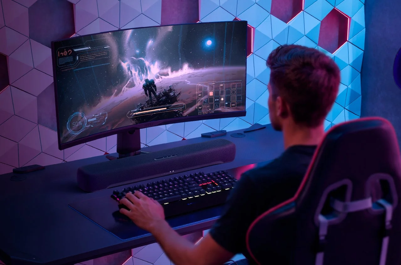 デスクのモニター下に置かれたB200Aと、ゲームをする男性
